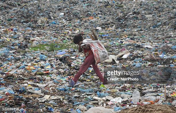An Indian girl with re-useable material walk pass by heaps of garbage at a dumping site on World Earth Day in Dimapur, India north eastern state of...
