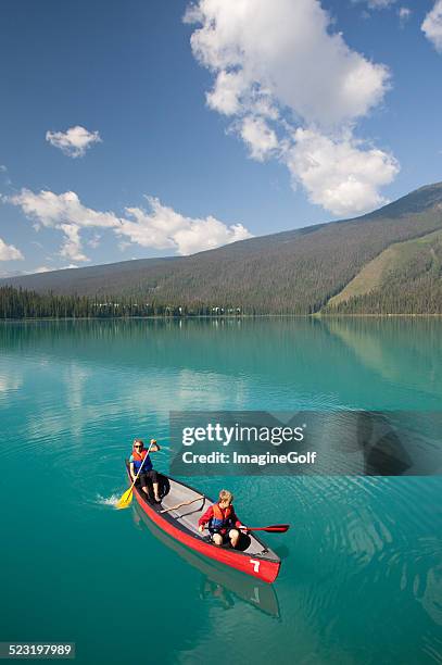 woman and young boy canoeing on beautiful mountain lake - family red canoe stock pictures, royalty-free photos & images
