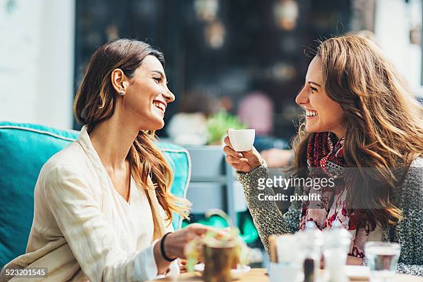 young women drinking coffee and smiling - female with friend in coffee stock pictures, royalty-free photos & images