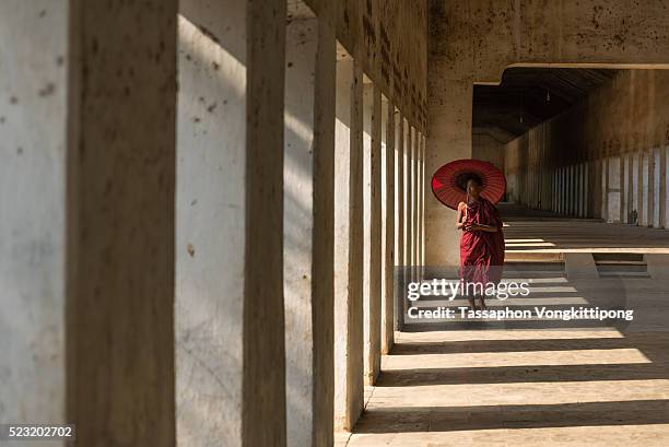 monk walking in the hall shadow holding umbrella - pagan stock-fotos und bilder