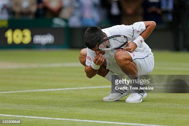 Novak Djokovic celebrates his victory over Roger Federer by eating a piece of the grass in the mens singles final on Centre Court during day thirteen...