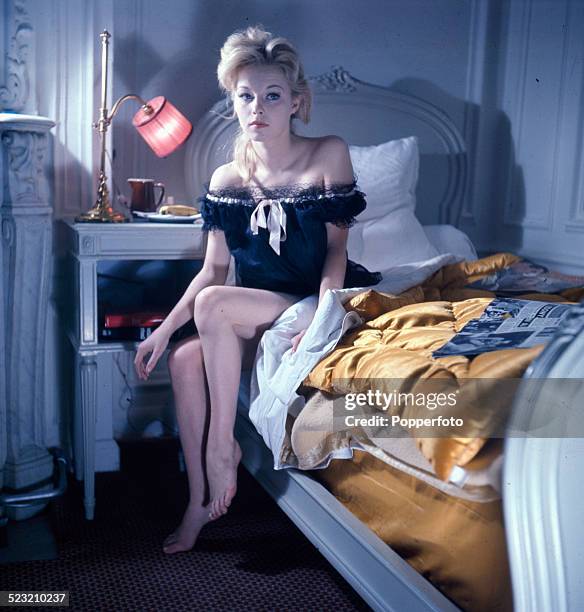 English actress Jill Haworth posed wearing a black lace lined negligee on the edge of a bed in 1963.