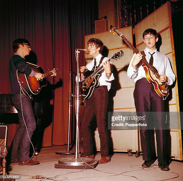 From left, John Lennon , George Harrison and Paul McCartney of English pop group The Beatles on stage during a recording session for the BBC Radio...