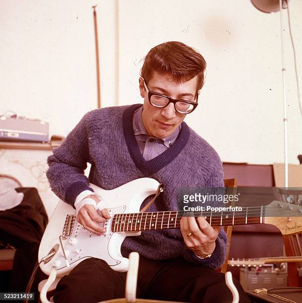 English guitarist Hank Marvin of The Shadows plays a white Fender Stratocaster guitar backstage in England in 1963.