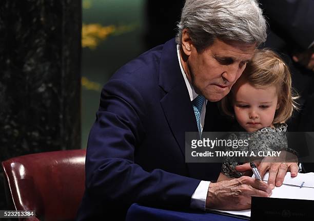 Secretary of State John Kerry signs the book holding his granddaughter, Isabelle Dobbs-Higginson, during the signature ceremony for the Paris...