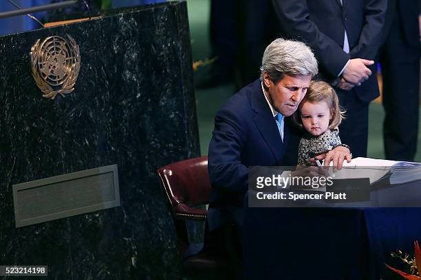 Secretary of State John Kerry holds his two year-old grand daughter Isabel Dobbs-Higginson for the signing of the accord at the United Nations...