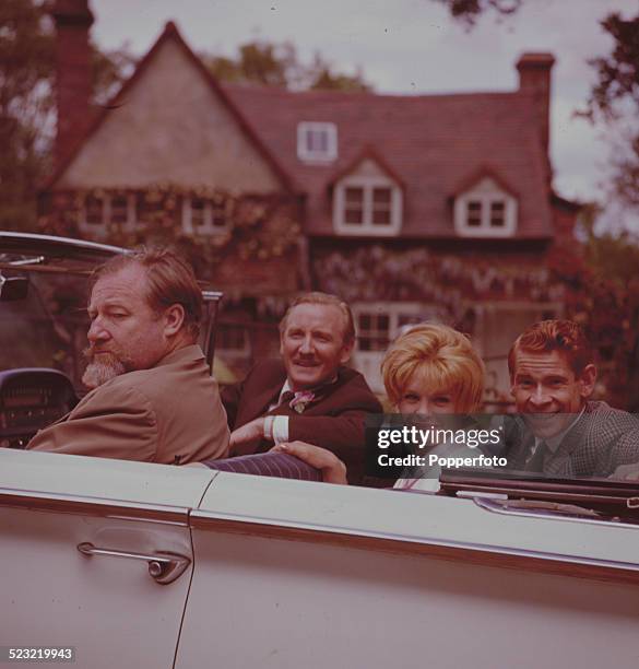 Actors James Robertson Justice , Leslie Phillips , Sally Smith and Stanley Baxter seated together in an open top car on the set of the film Father...