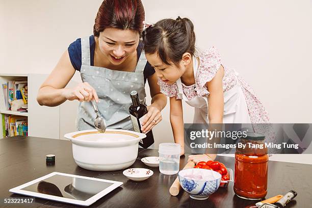 Mom cooking with toddler girl joyfully at home