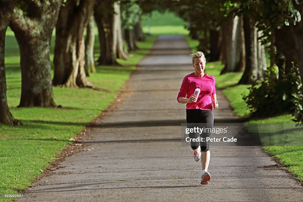 Woman in pink top running outside trough landscape