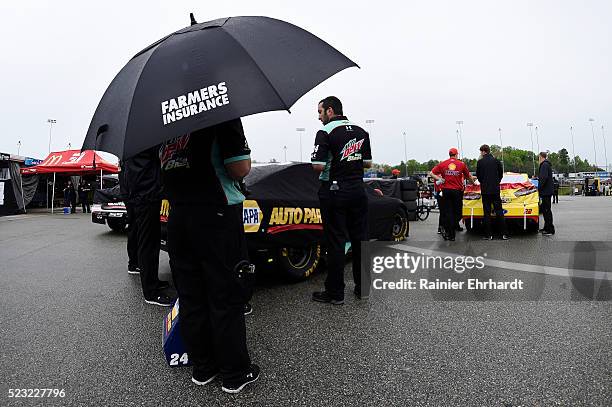 Crew member holds an umbrella in the garage area as it rains at Richmond International Raceway on April 22, 2016 in Richmond, Virginia.