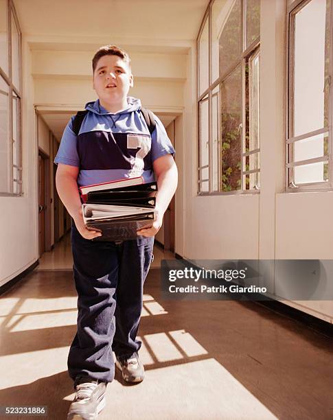 boy carrying books at school - chubby boy fotografías e imágenes de stock