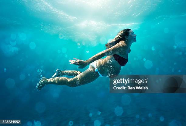 underwater view of pregnant woman swimming - aquatic sport stock-fotos und bilder