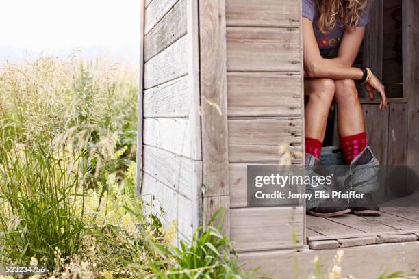 woman on toilet in outhouse - woman sitting on toilet stock-fotos und bilder