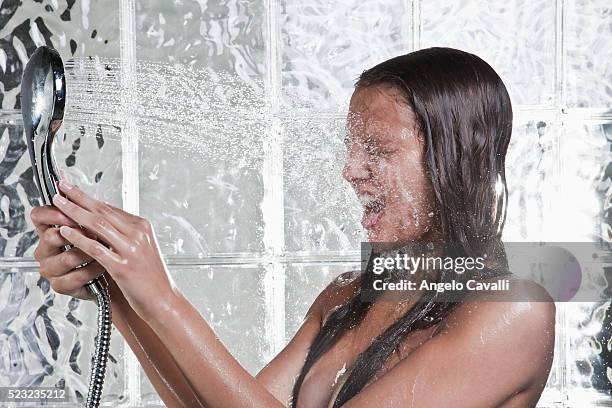 woman spraying self with showerhead - glass cube fotografías e imágenes de stock