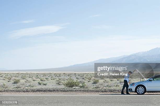 man with a broken down car in the desert - vehicle breakdown foto e immagini stock