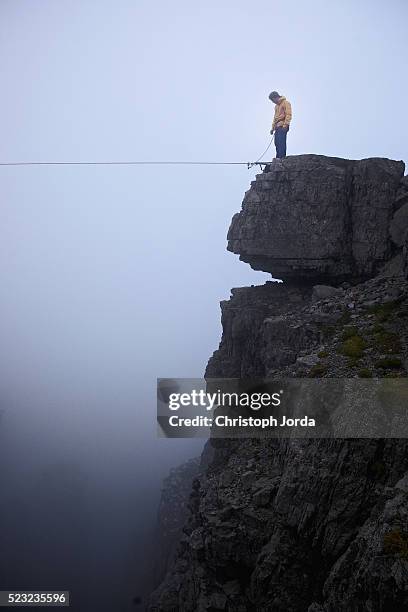 young man standing in front of high line in mountains, tirol, austria - tightrope walking stock-fotos und bilder