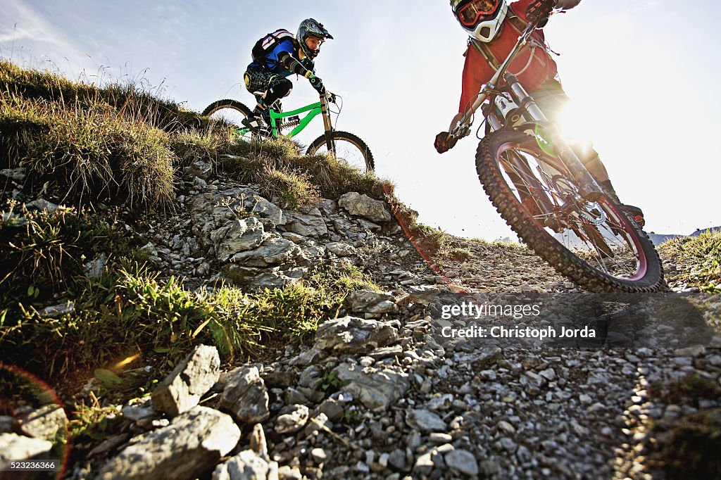 Two bikers riding down a trail