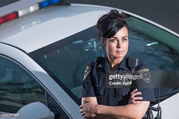 policial de pé ao lado do carro de polícia, braços cruzados - mulher polícia imagens e fotografias de stock