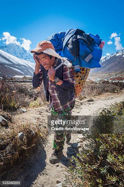 sherpa porter carrying heavy basket along trail himalayas nepal - buck teeth stockfoto's en -beelden