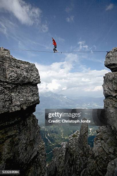 man balancing over high rope between two cliffs in mountains, tirol, austria - corda bamba - fotografias e filmes do acervo