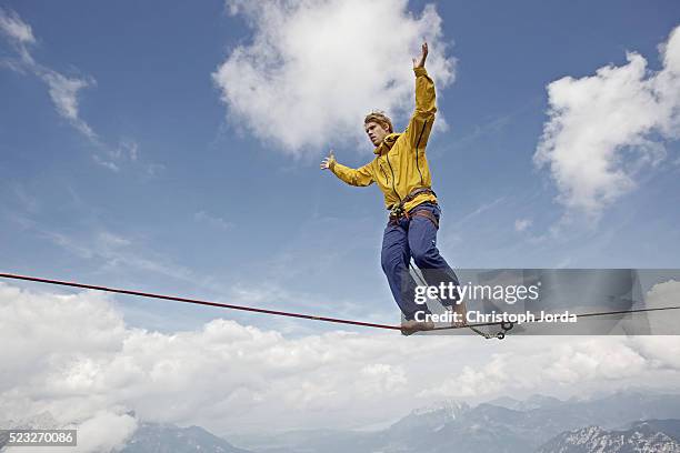 man balancing over high rope between two rocks in mountains, tirol, austria - tightrope walking stock-fotos und bilder