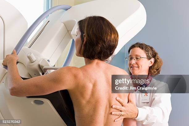 medical technician preparing patient for mammogram - mammographie photos et images de collection