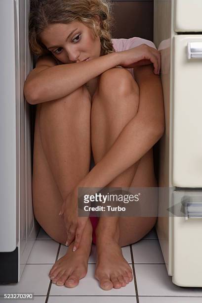 sad woman hiding in kitchen - woman curled up stock pictures, royalty-free photos & images