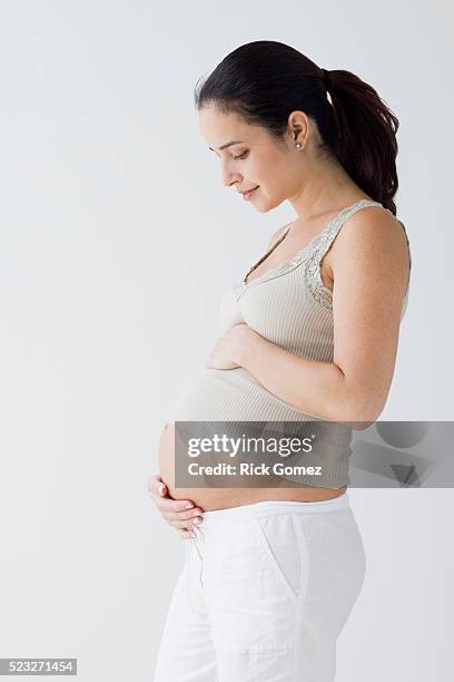 young pregnant woman holding stomach - embarazada fotografías e imágenes de stock