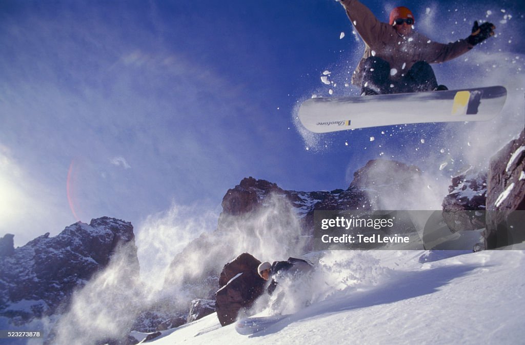 2 men snowboarding, one jumping off mountain, Jebel Toubkal, Morocco