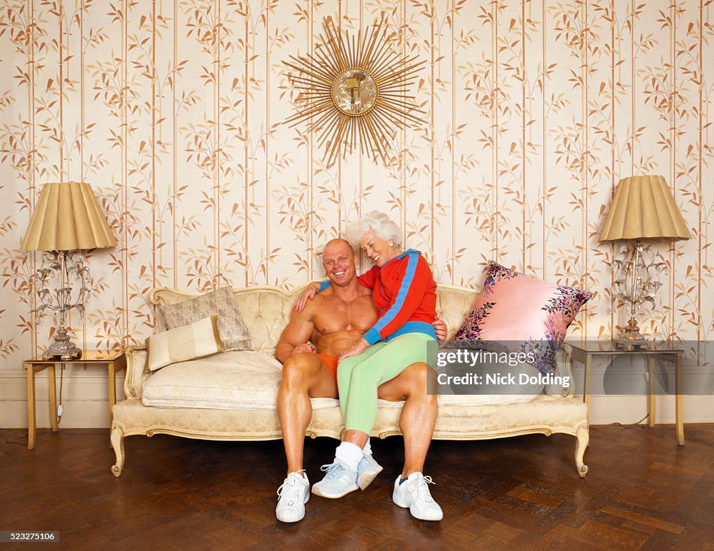Senior Woman Sitting on the Lap of a Young Muscular Man