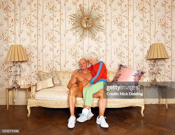 senior woman sitting on the lap of a young muscular man - juxtaposition stock-fotos und bilder