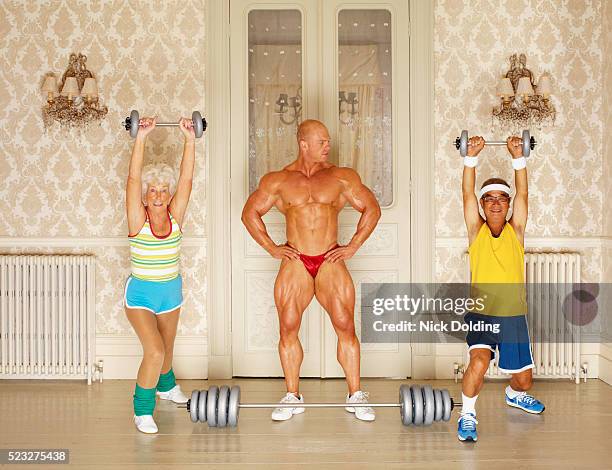 muscular man looking at two seniors weightlifting - body building stockfoto's en -beelden