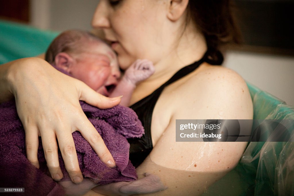 Mutter hält Neugeborenes in der Schwangerschaft Badewanne nach Hause Wassergeburt