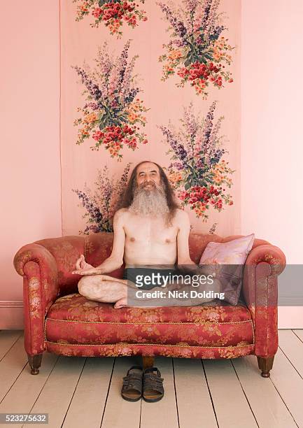 man in lotus position on couch - senior yoga stock-fotos und bilder