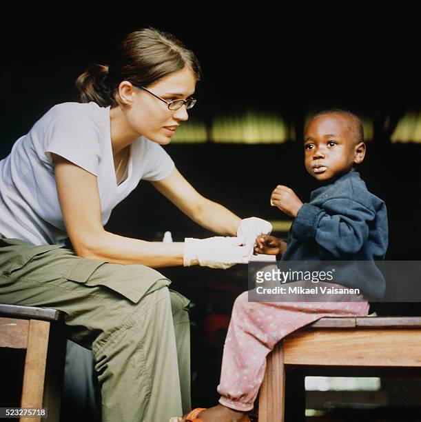 female doctor treating boy in ghana - humanitarian aid stock pictures, royalty-free photos & images
