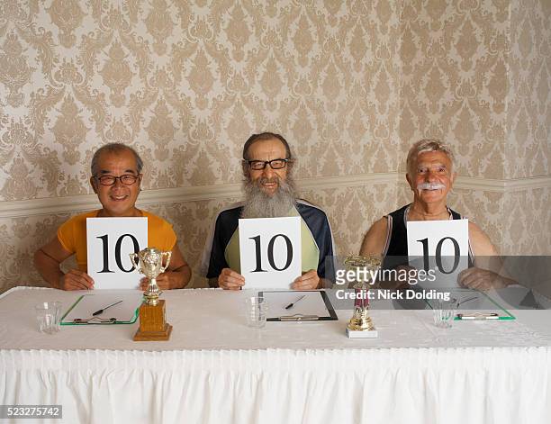 three smiling judges holding up perfect ten - scoring stockfoto's en -beelden