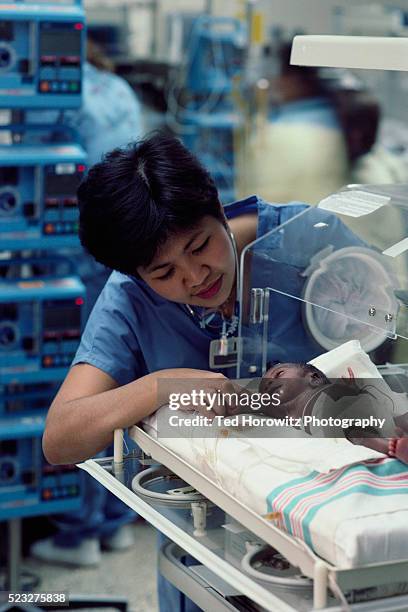 tending to premature baby in neonatal intensive care - 新生児集中治療室 ストックフォトと画像