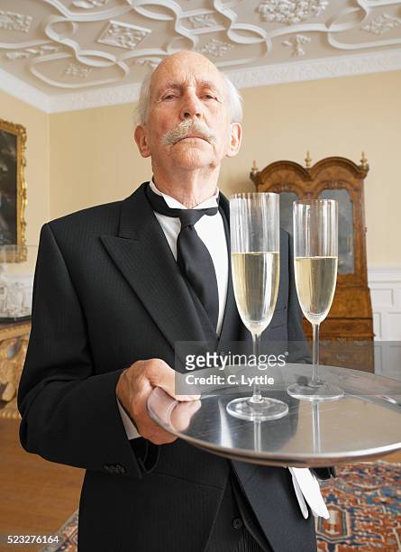 butler holding tray of champagne - buttler stock-fotos und bilder
