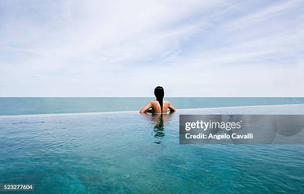 woman in pool looking to the sea and horizon - infinity pool - fotografias e filmes do acervo