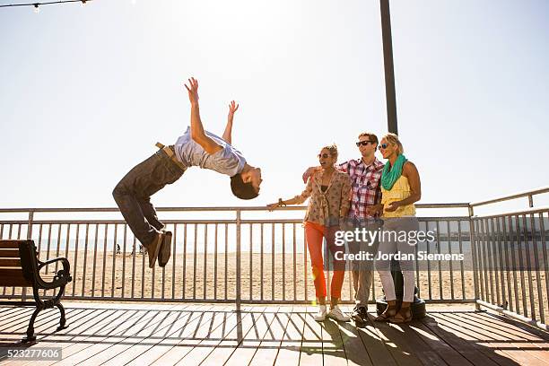 man doing backflip while his friends watch - fare le capriole all'indietro foto e immagini stock