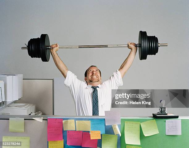 businessman lifting barbell at office - weight lifting stock-fotos und bilder