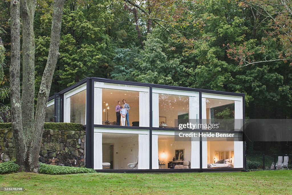 Family in Picture Window of Modern House