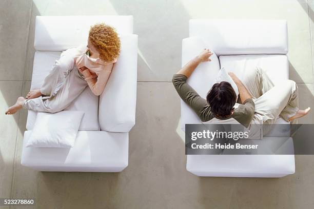 couple sitting on sofas - back to back stock pictures, royalty-free photos & images