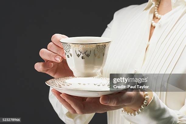 woman holding ornate gilded tea cup and saucer - etiquette stock-fotos und bilder