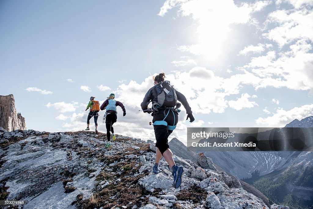 Trail running friends ascend mountain ridge