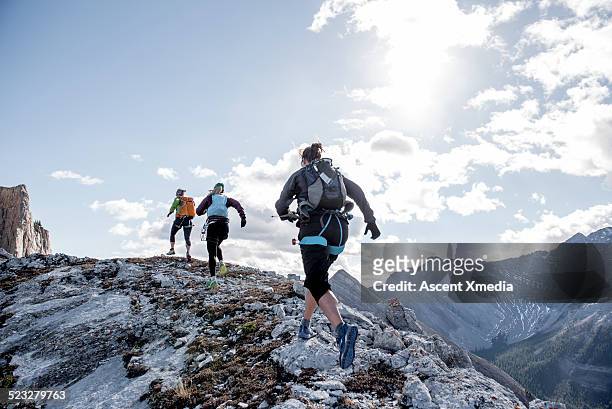 trail running friends ascend mountain ridge - seguir actividad móvil general fotografías e imágenes de stock