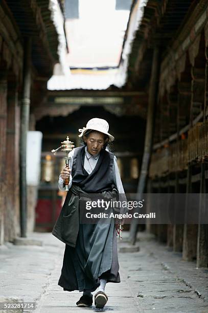 tibetan woman with buddhist prayer wheel at jokhang monastery, lhasa, tibet, china - prayer wheel stock pictures, royalty-free photos & images