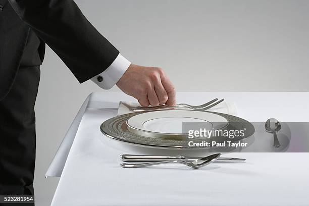 waiter setting the table with fine china and silver - regole dell'etichetta foto e immagini stock