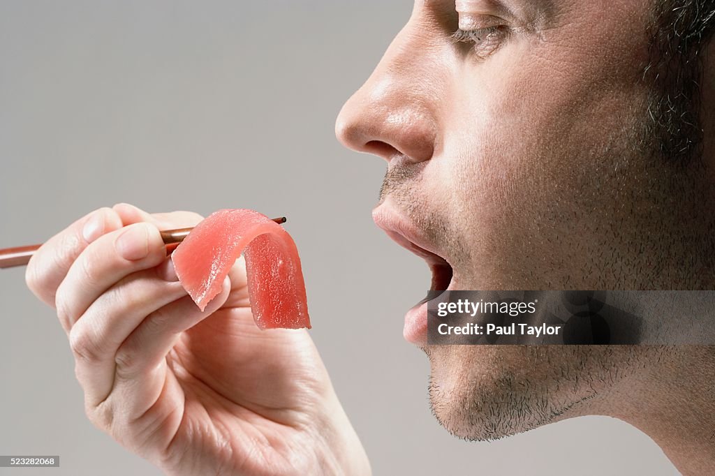 Man eating piece of sashimi