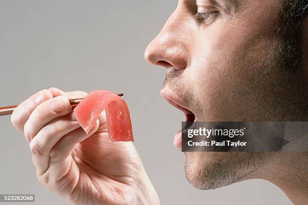 man eating piece of sashimi - human mouth stock pictures, royalty-free photos & images